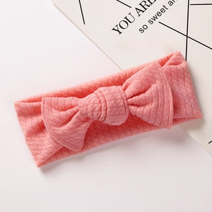 Close-up of soft pink ribbed knit baby headband with a large decorative bow detail