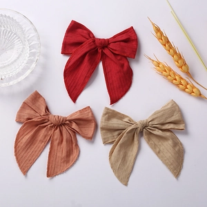 Three 6-inch cotton jacquard bow hair clips in dark red, brick, and khaki on white