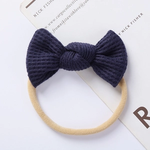 Detail of dark blue waffle knit bow with a beige high-elastic seamless headband