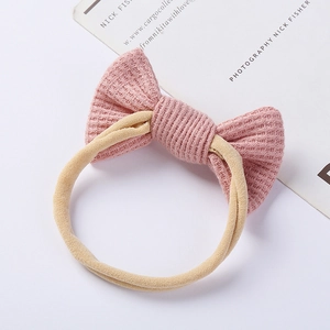 Close-up of pink waffle knit bow headband with beige high-elastic seamless band for babies
