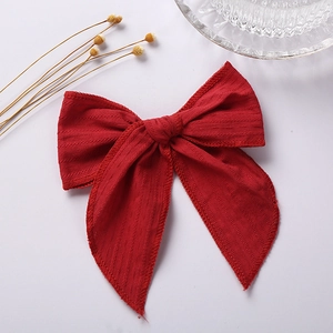 Detail of red 6-inch jacquard cotton bow hair clip with textured fabric and scalloped edges