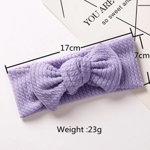 Detail view of purple ribbed knit baby headband with a large bow and 17cm length