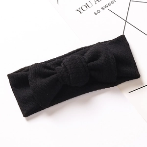 Detail of black ribbed cotton baby headband with elastic bow and soft knit texture