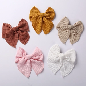 Detailed set of five large muslin bow hair clips in rust, yellow, beige, pink, and white