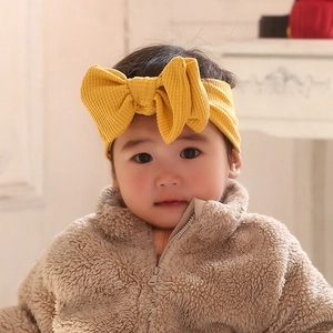 Detailed close-up of bright yellow waffle knit baby headband with a large handmade bow