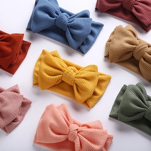 Macro detail of various colorful waffle-knit baby headbands with large handmade bows