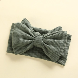Close-up of green waffle knit texture and large handmade bow on infant headband
