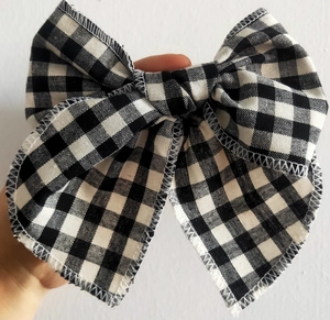 Détail montrant le tissu vichy texturé et les bords cousus du nœud papillon noir et blanc