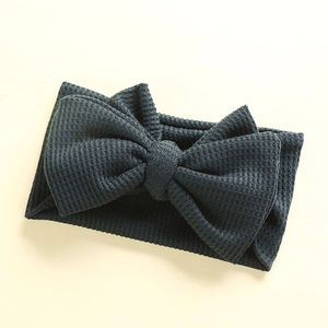 Detail showing the waffle knit texture of a charcoal grey oversized baby headband bow