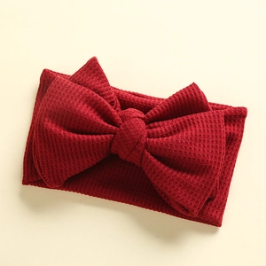 Detail of baby headband featuring deep red waffle knit texture and large DIY bow