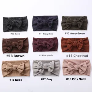 Detail view of nine-color ribbed knit baby headbands with bow ties on white background