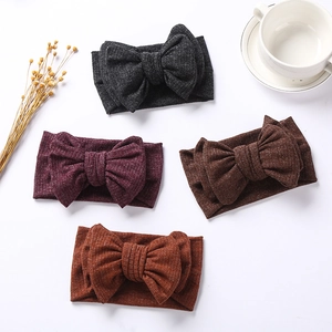 Flat lay of four ribbed knit infant headbands with oversized bows in classic earth tones