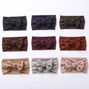 Close-up of nine ribbed knit baby headbands with large bows in various soft colors