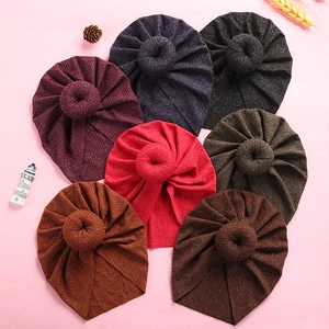Detail view of seven soft ribbed knit baby turbans with donut knots in various warm colors