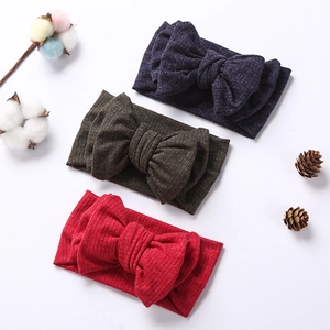 Detailed close-up of three knitted baby headbands with oversized bows in a flat lay view