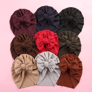 Detail showing nine colors of ribbed knit baby turban hats with large bow accents