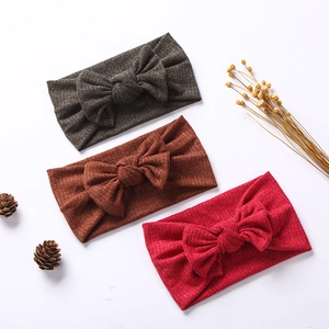 Flat lay of three ribbed knit baby headbands with large bows in red and brown colors