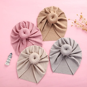 Flat lay of four ribbed knit baby donut turbans in pink, brown, beige, and grey colors