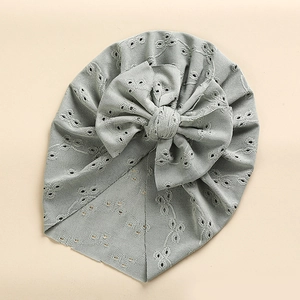 Detail of baby turban hat in sage green with hollow embroidery and large bow decoration