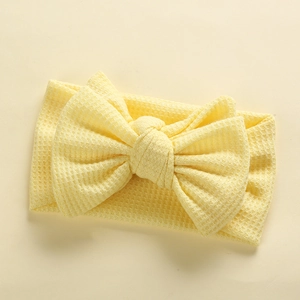 Detail of baby waffle headband featuring a large bow in soft pastel yellow fabric