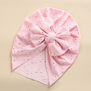 Detail of baby lace turban hat in light pink featuring a large decorative bow