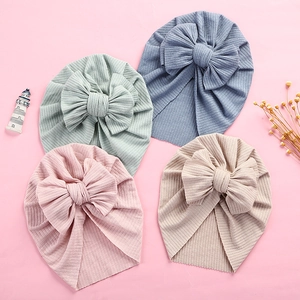 Detailed flat lay of ribbed baby turban hats in pink, green, blue, and beige colors