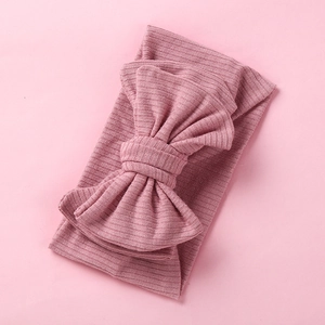 Detailed view of pink ribbed knit texture and large bow on soft baby headband