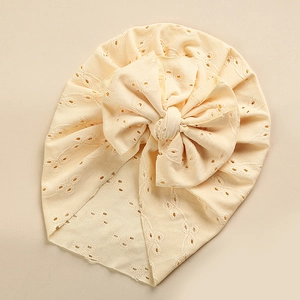 Detail of baby turban hat with delicate hollow eyelet embroidery and a large bow