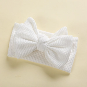 Close-up of white waffle knit elastic baby headband with a large double-layered bow