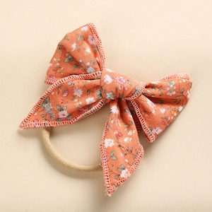 Dettaglio del fiocco in cotone a fiori arancioni con fascia in nylon beige ad alta elasticità