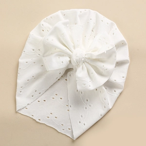 Detailed close-up of white baby turban hat with eyelet embroidery and a layered bow