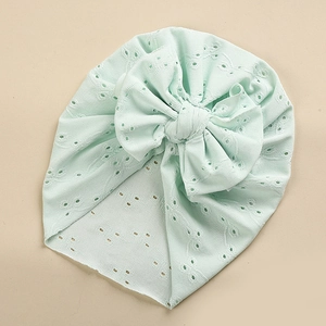 Detail of mint green lace baby turban with hollow embroidery and large bow decoration