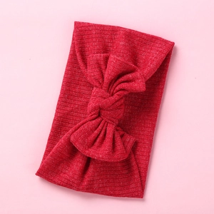 Detail of red ribbed knit baby headband with a soft elastic bow on a pink background