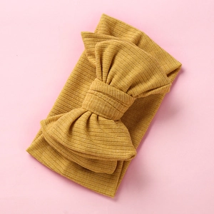 Elastic mustard yellow knitted baby headband featuring a large oversized ribbed bow knot