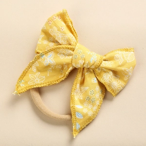 Dettaglio del fiocco in cotone giallo a fiori per neonati con morbida fascia in nylon
