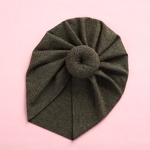 Detail of dark green ribbed knit baby turban with donut knot on pink background