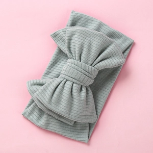 Detail view of light grey ribbed knit fabric and oversized bow on toddler headband