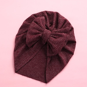 Detailed texture of dark red ribbed baby turban hat featuring a large soft knit bow