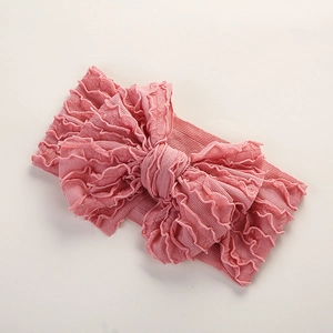 Détail d'un bandeau pour bébé à nœud rose avec texture côtelée et bords à volants doux