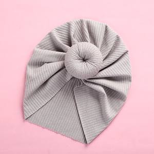 Macro detail of a light grey baby donut turban hat with vertical ribbed knit and pleats