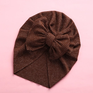 Detail of soft ribbed knit baby turban hat in brown with large bow decoration