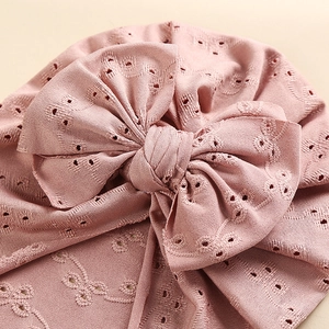 Close-up of pink baby hat featuring delicate hollow embroidery and a large bow design