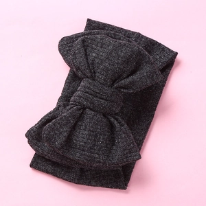 Detailed texture of dark grey knitted wide headband with oversized matching bow