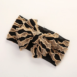 Détail du bandeau bébé avec un grand nœud noir superposé et des bords en dentelle