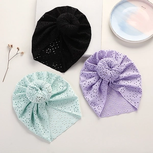Three baby turban beanie hats with donut knots and lace cutouts in black, green, and purple