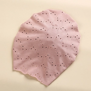Detailed close-up of pink lace knit baby hat showing hollow point pattern and wavy edges