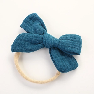 Détail d'un bandeau bébé en mousseline montrant le tissu bleu paon et l'élastique souple