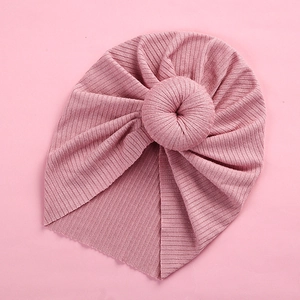 Detail of baby turban hat featuring a pink donut knot and elastic ribbed knit fabric