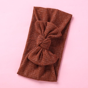 Detail view of deep caramel ribbed knit baby headband with a soft wide bow knot