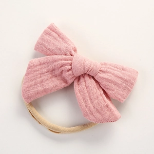 Détail du nœud en double gaze de coton rose sur un bandeau en nylon pour bébés